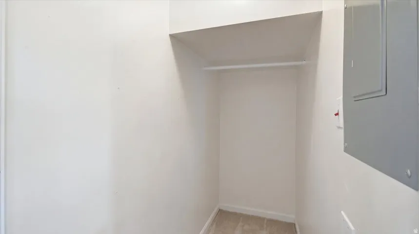 Built-in closet with hanging rod, overhead shelving, and neutral carpeting