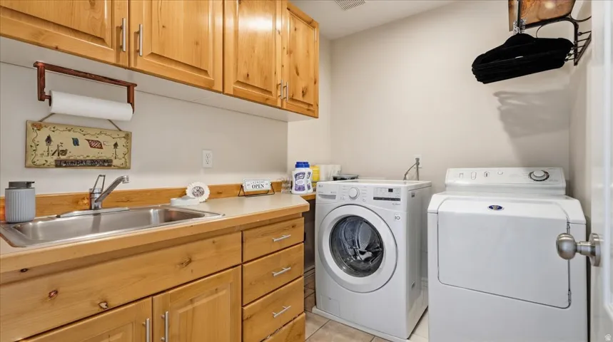 Laundry area featuring wood-finish cabinetry, a utility sink, and ample countertop space