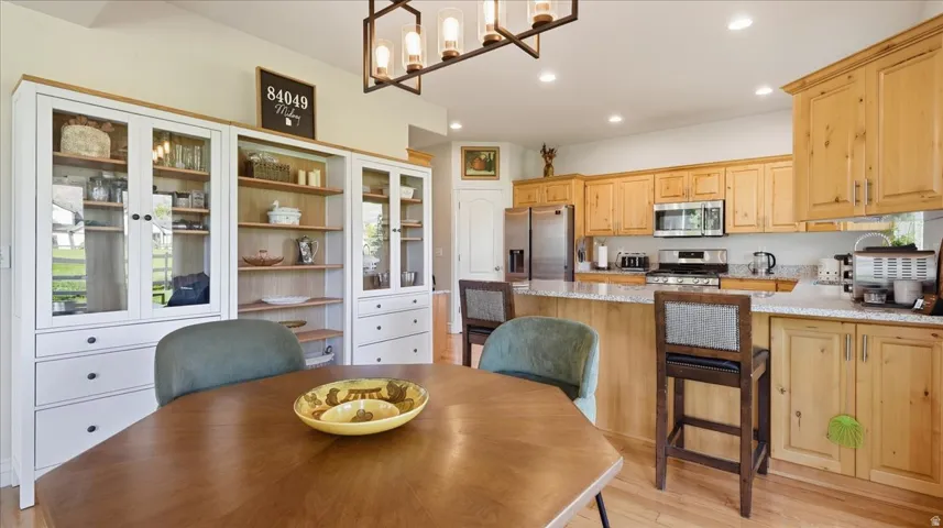 Kitchen featuring wood-finish cabinetry, stainless steel appliances, a breakfast bar with stone countertops, recessed lighting, and a decorative chandelier