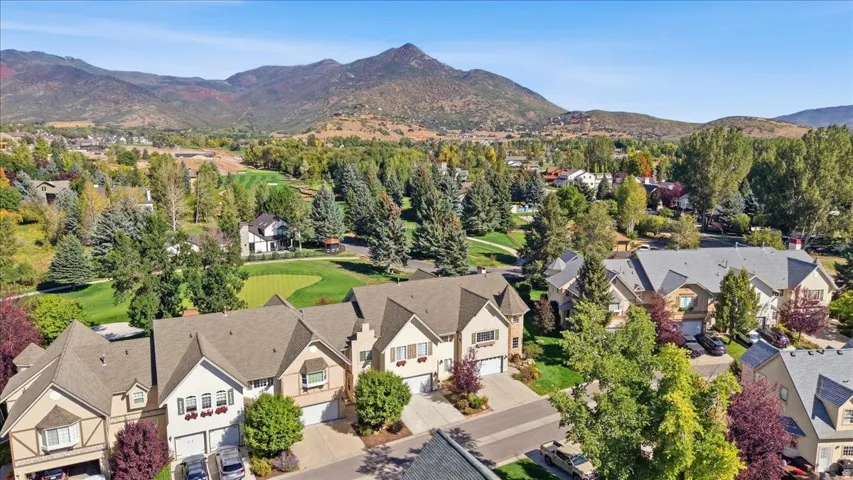 Residential properties with attached garages, surrounded by mature trees and landscaping