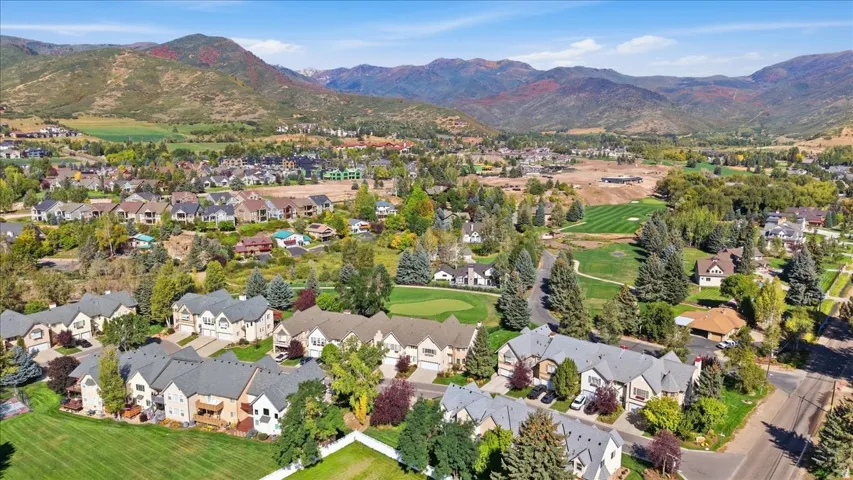 Expansive residential community with diverse architectural styles, surrounded by mature trees and mountain scenery