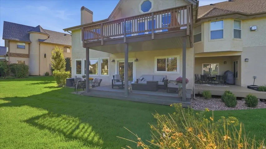 Spacious backyard featuring a manicured lawn, an upper-level wood deck, a lower-level concrete patio, a covered lower-level wood deck, and multiple large windows