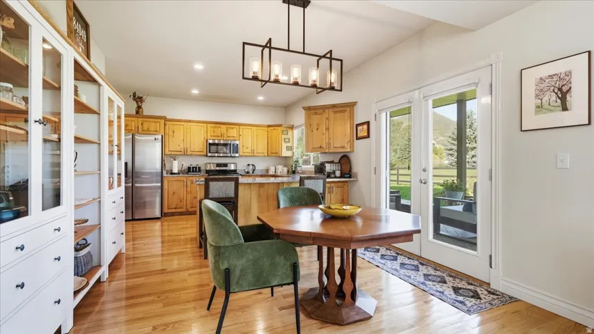 Kitchen featuring wood cabinetry, stainless steel appliances, wood-finish flooring, and vaulted ceilings