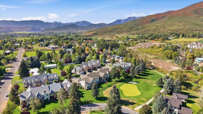 Expansive green spaces with mature trees, residential properties, a golf course, and distant mountains
