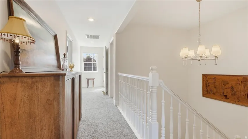 Carpeted hallway with a white spindle railing and a window featuring muntins