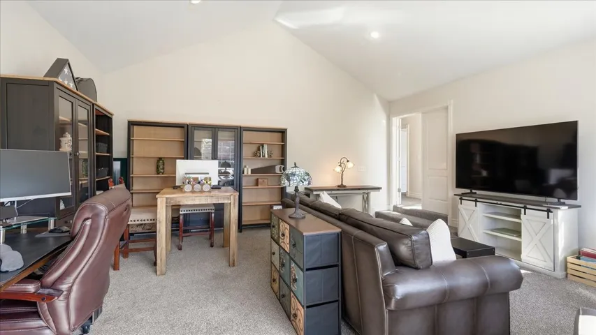 Vaulted ceiling, recessed lighting, built-in shelving, white walls, and carpet flooring