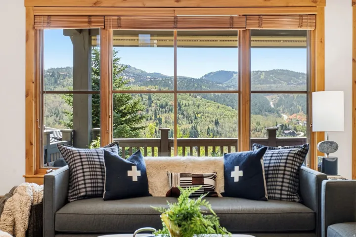 Expansive multi-pane window with wood-finish trim, offering a mountain backdrop, and featuring a balcony with wood railings