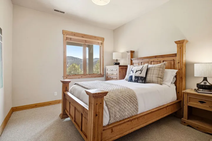 Brightly lit room featuring a window with a natural wood frame, vaulted ceiling, and neutral-toned wall paint