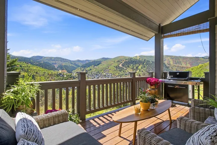 Expansive outdoor deck with mountain scenery, wood-finish flooring, and a covered ceiling