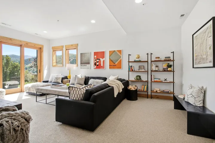 Sliding glass door with wood trim, recessed lighting, two windows with wood trim, and wall-mounted shelving