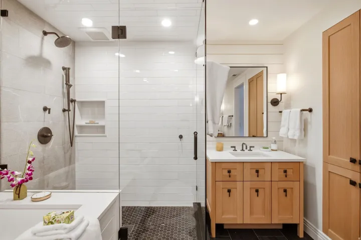 Glass-enclosed shower with subway tile and hexagon tile flooring