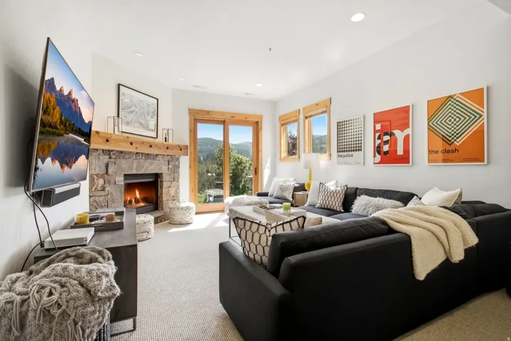 Stone-clad fireplace with a wood mantle, sliding glass doors, recessed lighting, and wall-to-wall carpeting