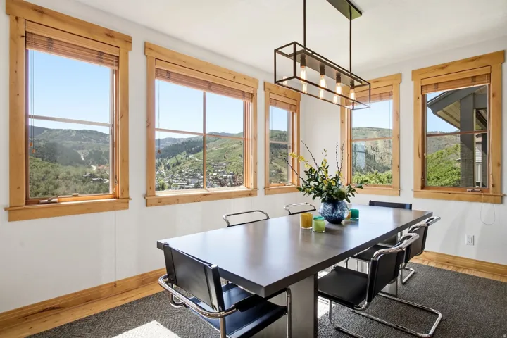 Dining space with multiple windows, wood trim, and a linear chandelier