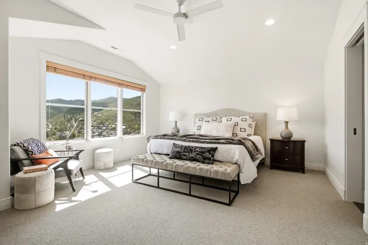 Spacious room featuring vaulted ceilings, a large three-panel window, wall-to-wall carpeting, and recessed lighting