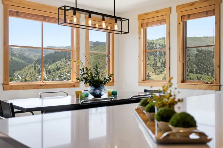 Solid surface countertop, wood-trimmed windows, recessed lighting, and a linear pendant light fixture