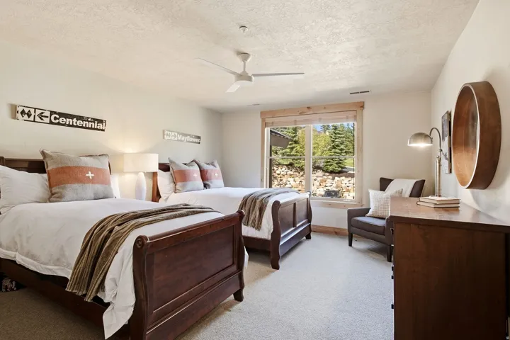 Wood-finish sleigh beds, a ceiling fan, and carpeted flooring