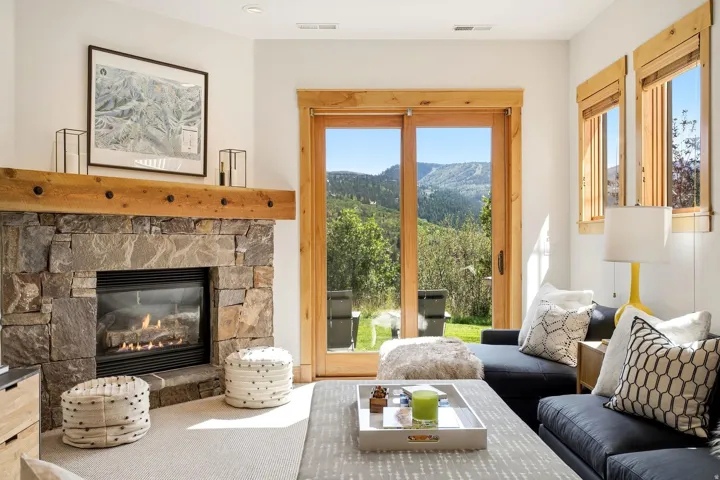 Stone-clad fireplace with a substantial wood mantel, glass sliding doors, wood-trimmed windows, and recessed lighting