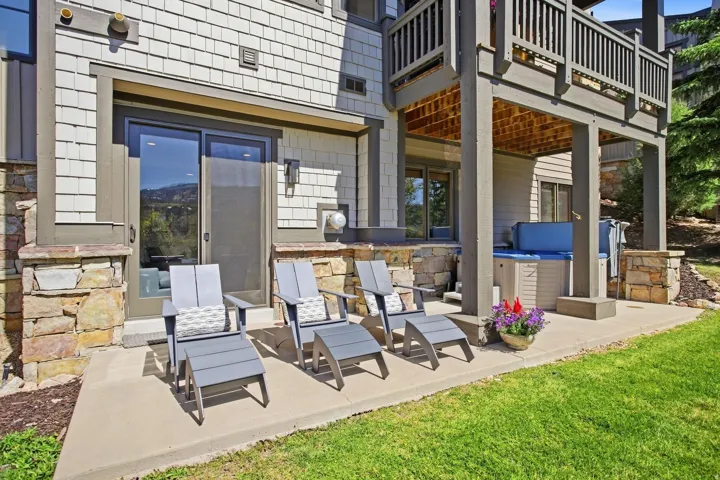 Ground-level patio with a built-in hot tub, solid concrete surface, and stacked stone accents