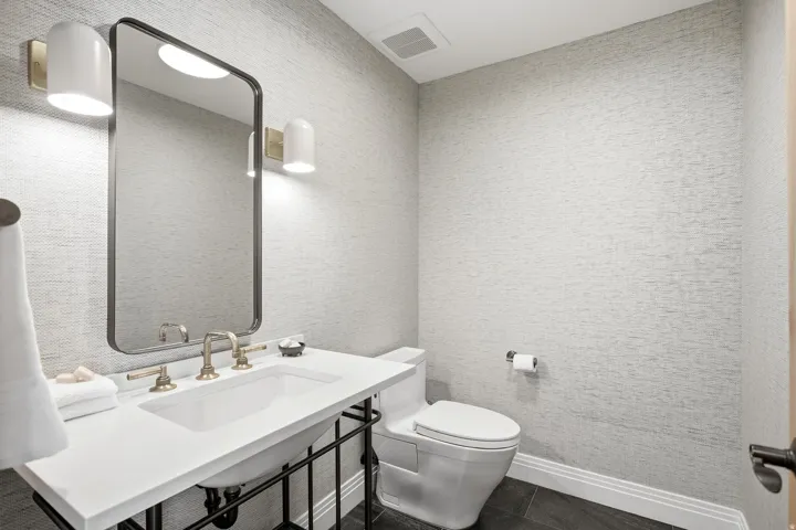 Vanity with white countertop and integrated rectangular sink, brass-finish faucet, and coordinating wall sconces