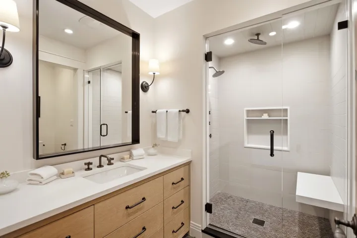 Floating vanity with wood-finish cabinetry and dark bronze hardware