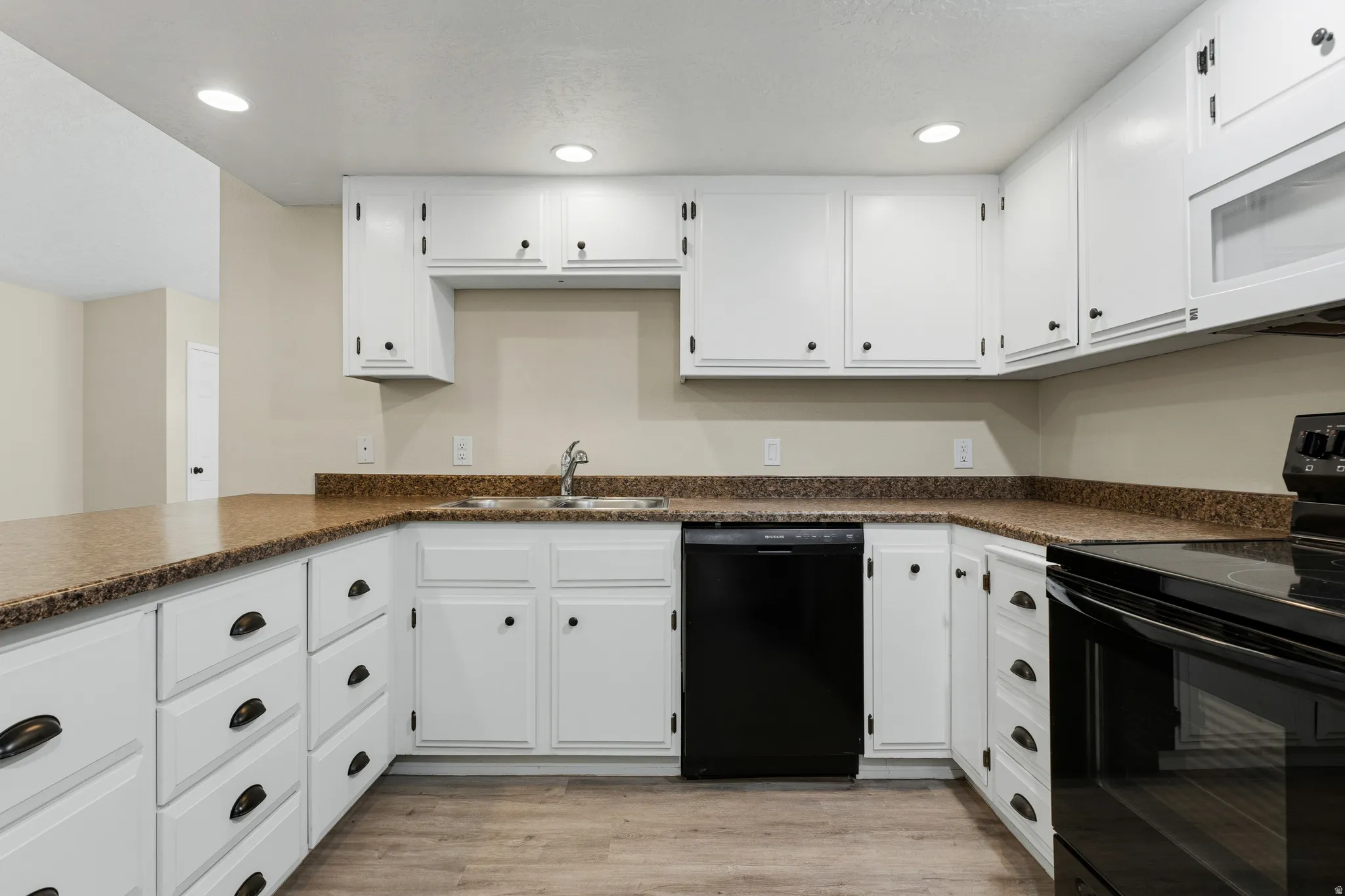 Kitchen featuring white cabinetry, dark hardware, granite-style countertops, wood-finish flooring, and recessed lighting