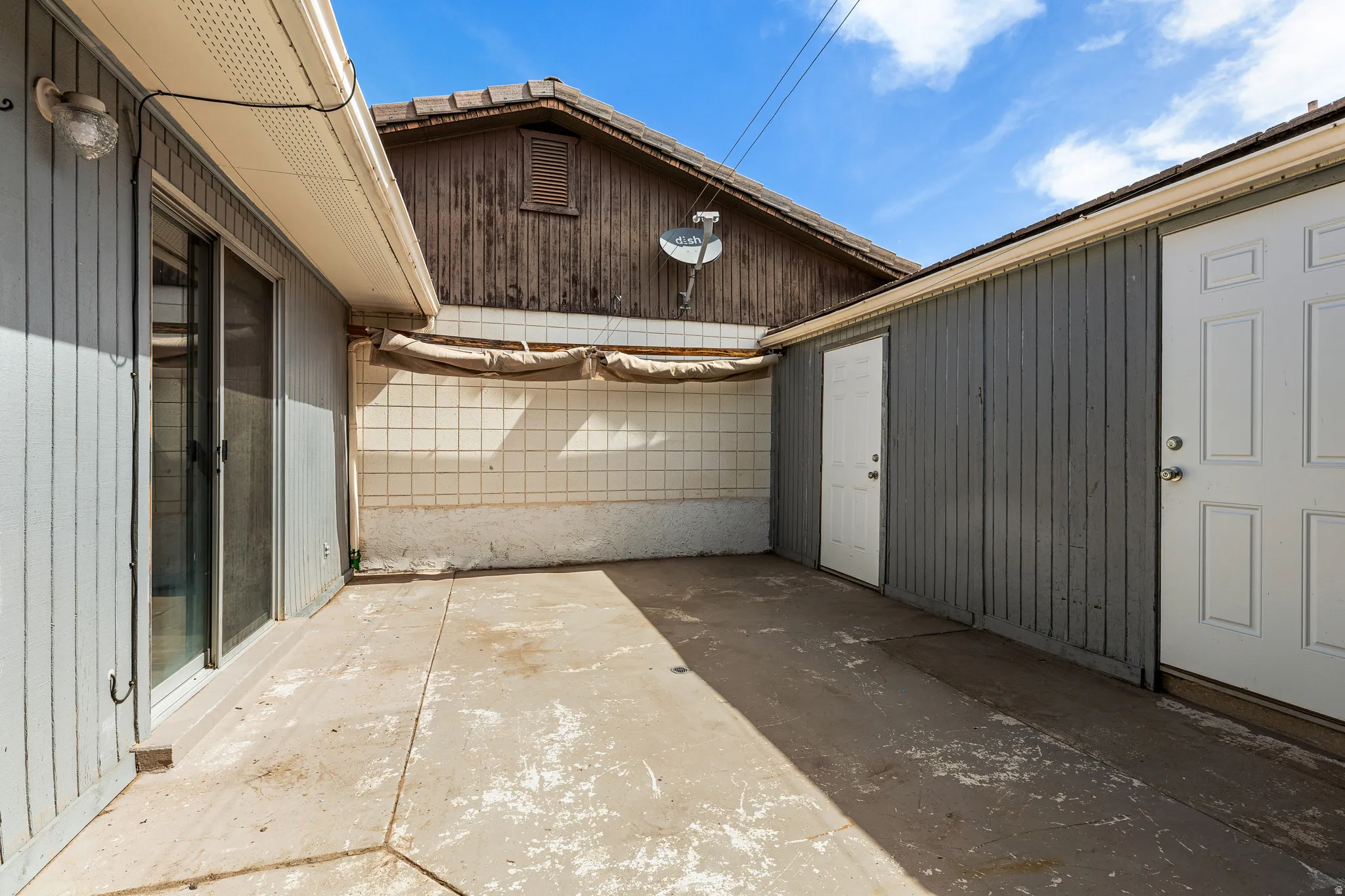 Concrete patio area with a sliding glass door and two side doors