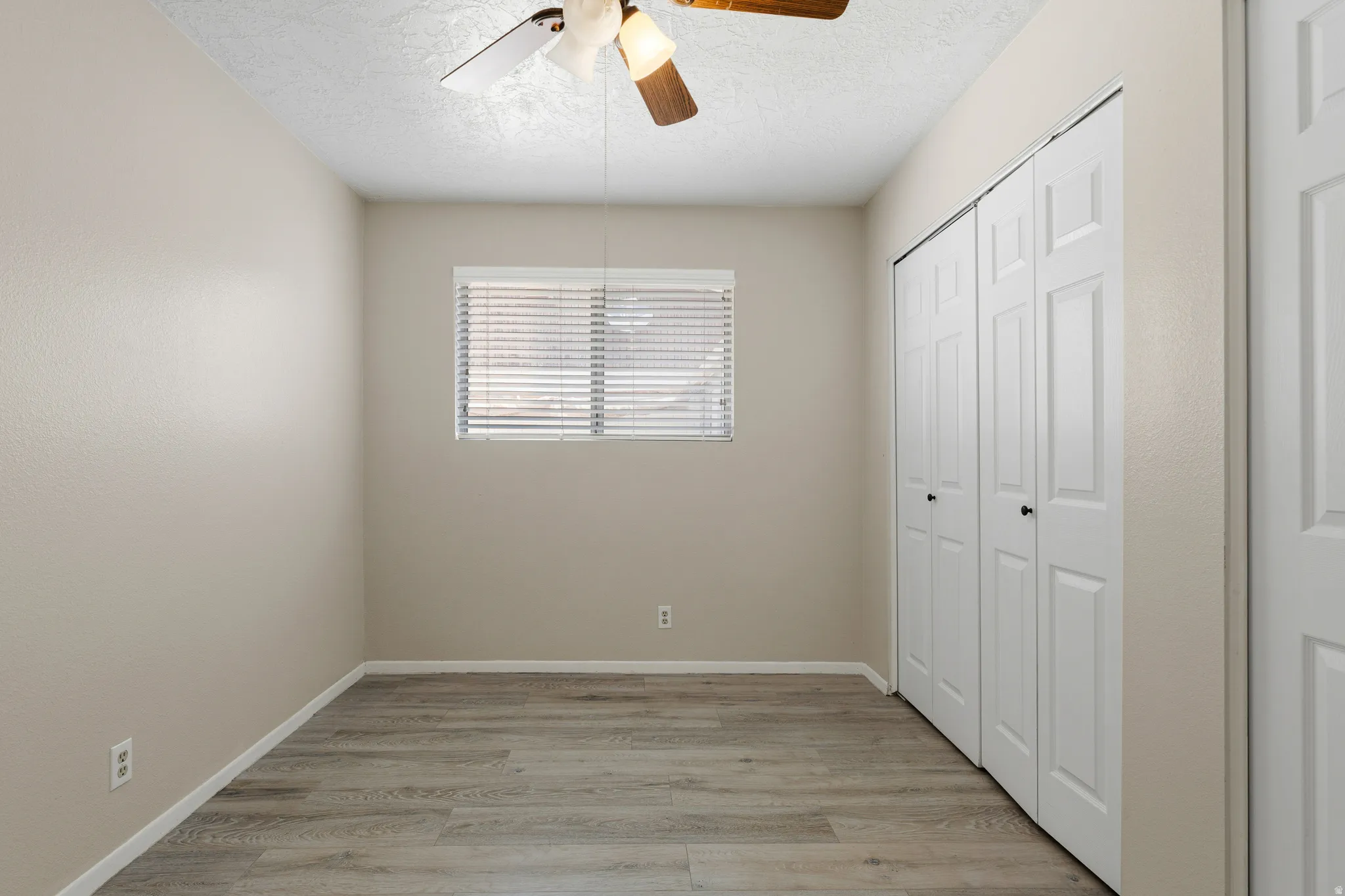 Wood-finish flooring, neutral wall tones, white blinds, and a ceiling fan with light fixture