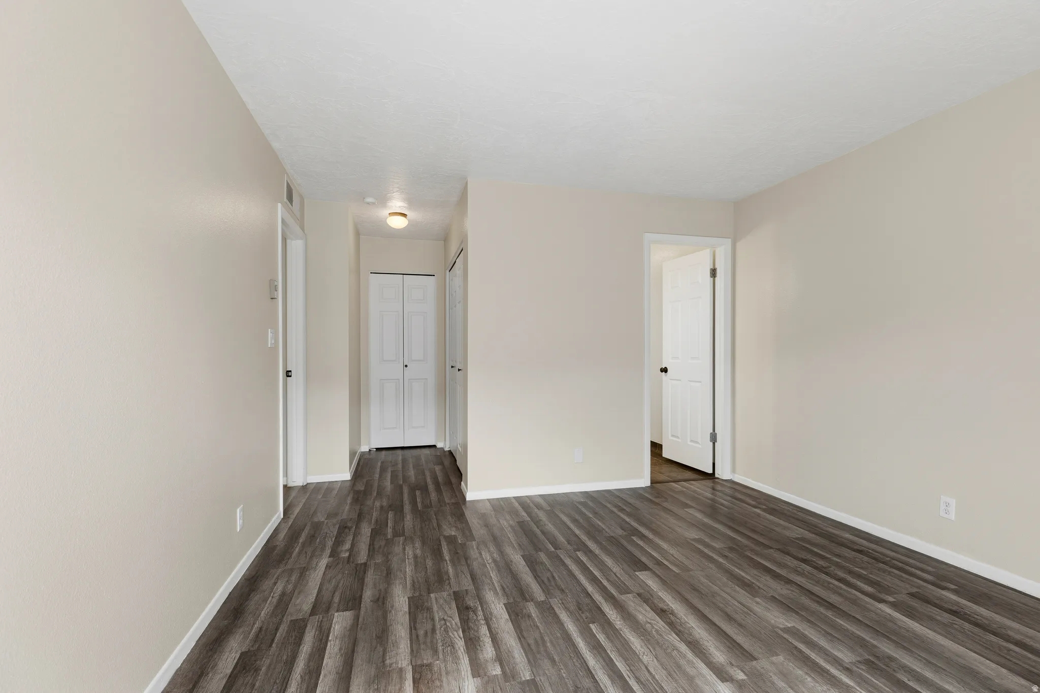 Wood-finish flooring throughout, smooth textured walls, white trim, and recessed lighting