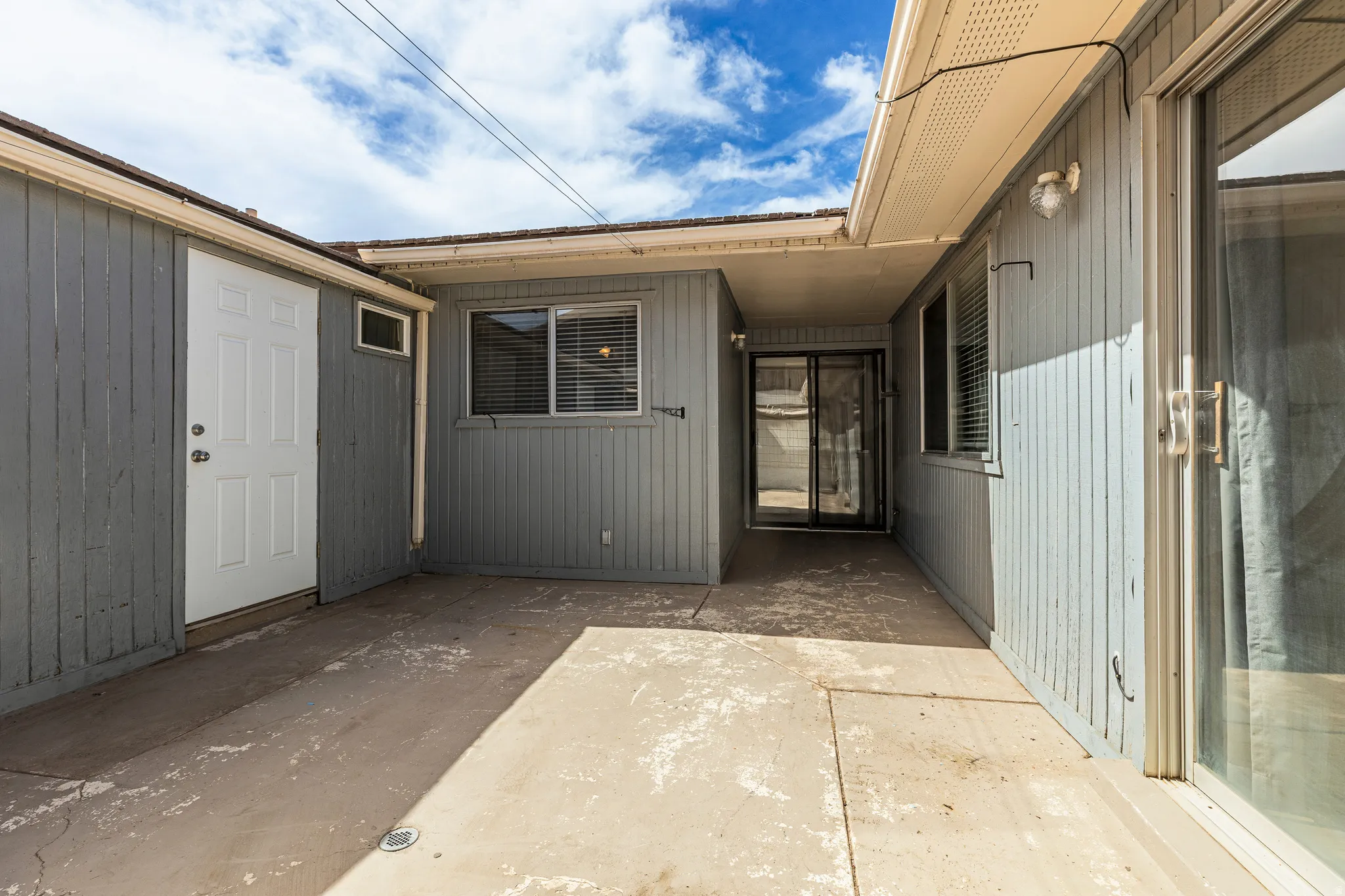 Concrete patio area with vertical wood siding and an exterior door