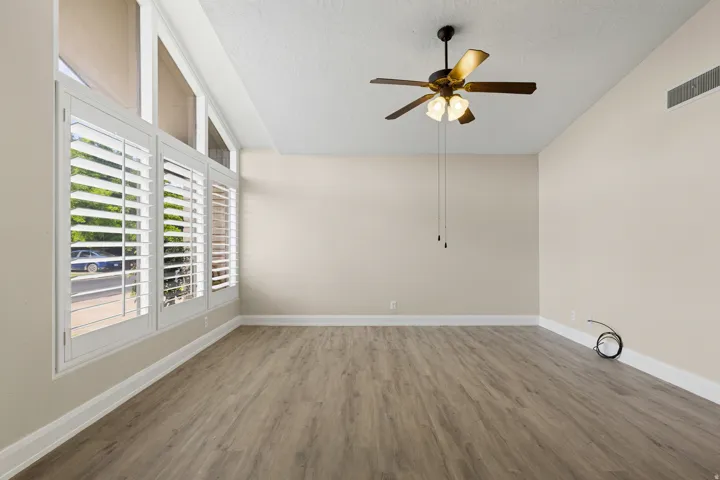 Vaulted ceiling with a ceiling fan, wood-finish flooring, and white window shutters