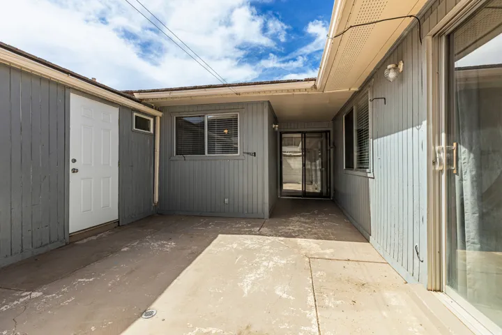 Concrete patio area with vertical wood siding and an exterior door