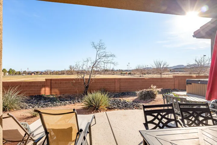 Covered patio with concrete flooring, desert landscaping, and a privacy wall