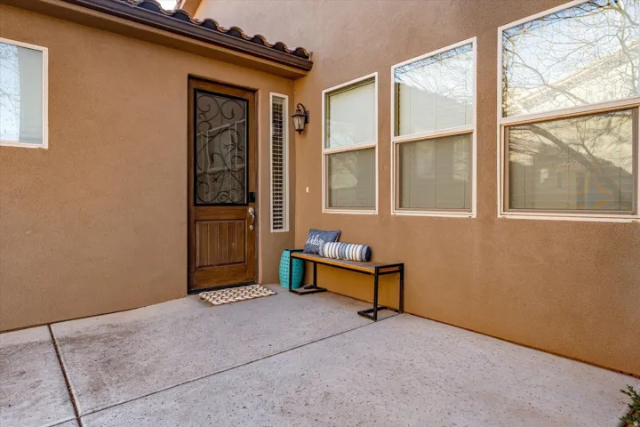 Stucco exterior with a wood-panel entry door, decorative security screen, and multiple windows