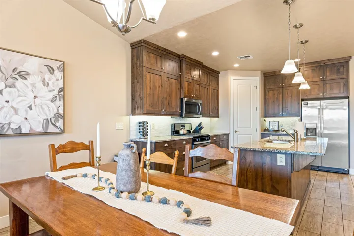 Kitchen featuring wood-finish cabinetry, stainless steel appliances, granite countertops, and tile flooring