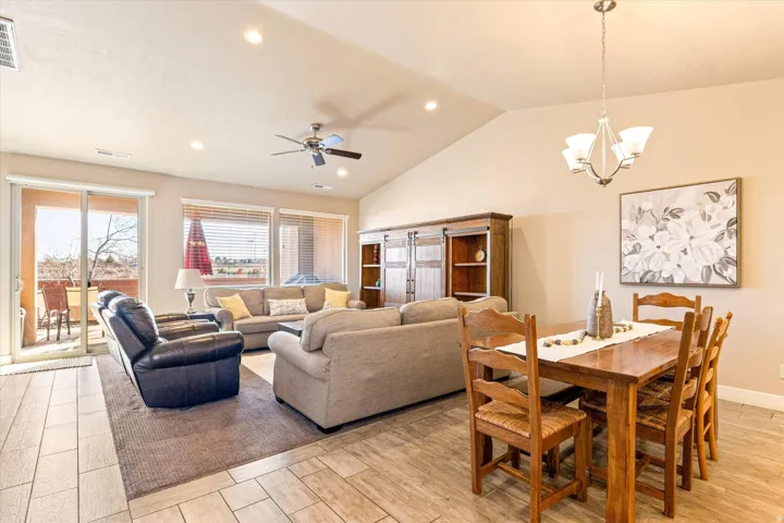 Vaulted ceilings, recessed lighting, wood-finish flooring, sliding glass door, and a ceiling fan with light fixture