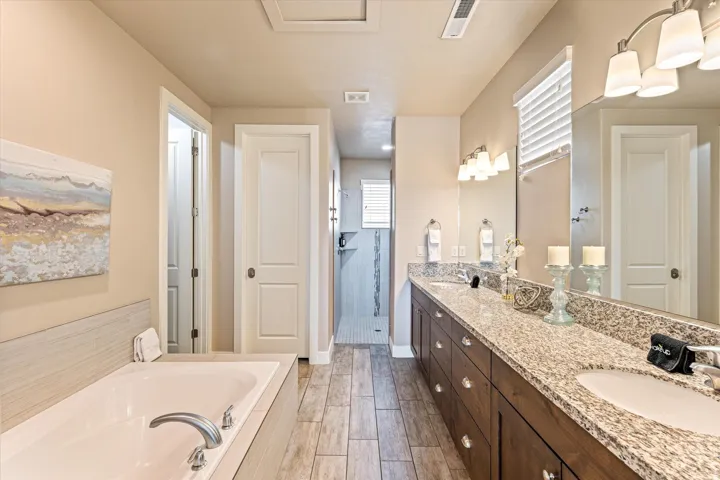 Dual vanity with light-toned countertop, wood-finish cabinetry, and undermount sinks