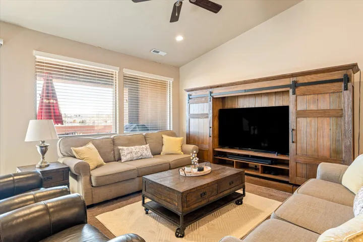 Vaulted ceilings, recessed lighting, ceiling fan, dual windows with blinds, and a built-in media console with barn doors