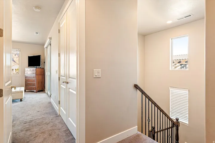 Carpeted hallway with white paneled doors and recessed lighting
