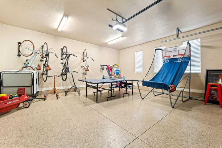 Garage space featuring an epoxy-coated floor, multiple wall-mounted storage solutions, recessed lighting, and overhead garage door tracks