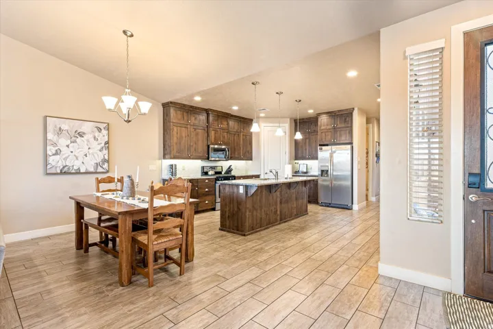 Open-concept kitchen featuring wood-finish cabinetry, stainless steel appliances, a center island with pendant lighting, and wood-finish flooring throughout