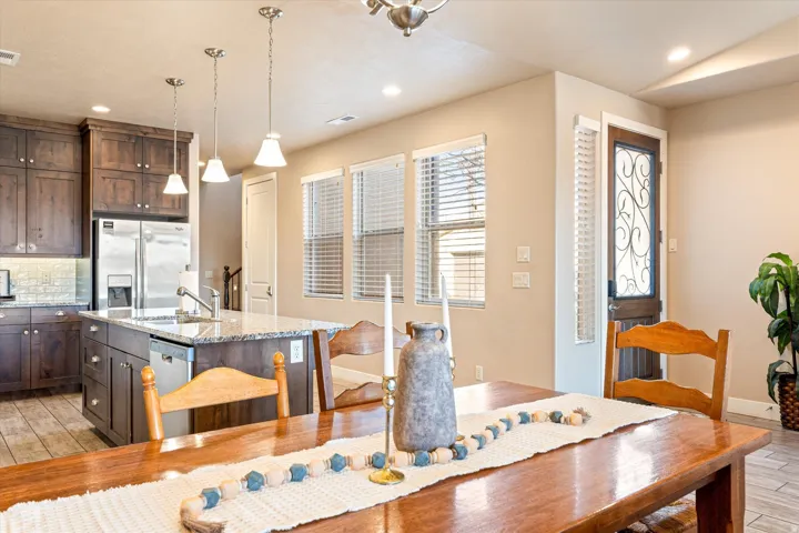 Kitchen island with granite countertop, dark wood-finish cabinetry, stainless steel appliances, and pendant lighting