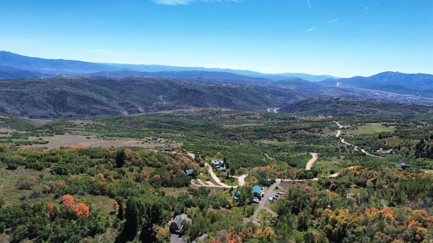Expansive mountainous terrain with varied tree coverage and winding natural roads