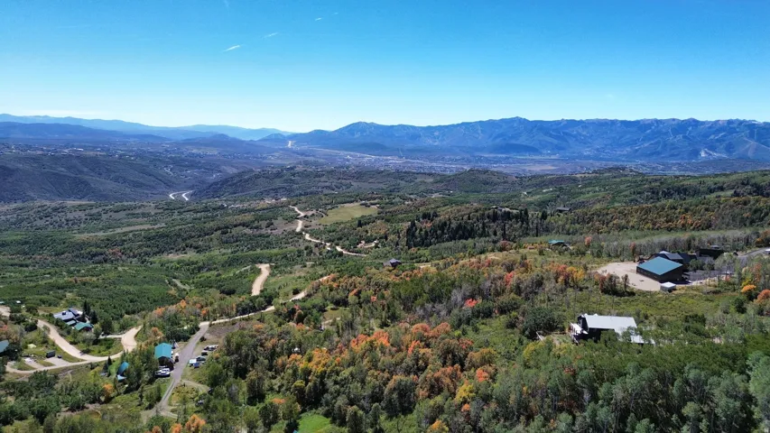 Expansive mountain landscape with scattered residential properties, winding roads, and varied tree coverage