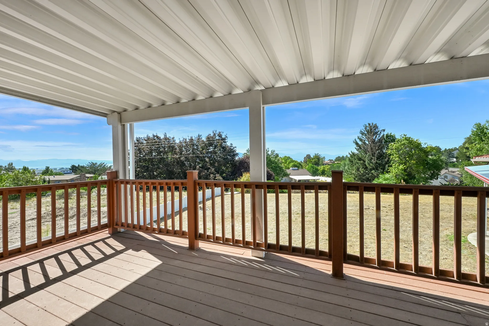 Covered deck with wood-finish railing and distant water scenery