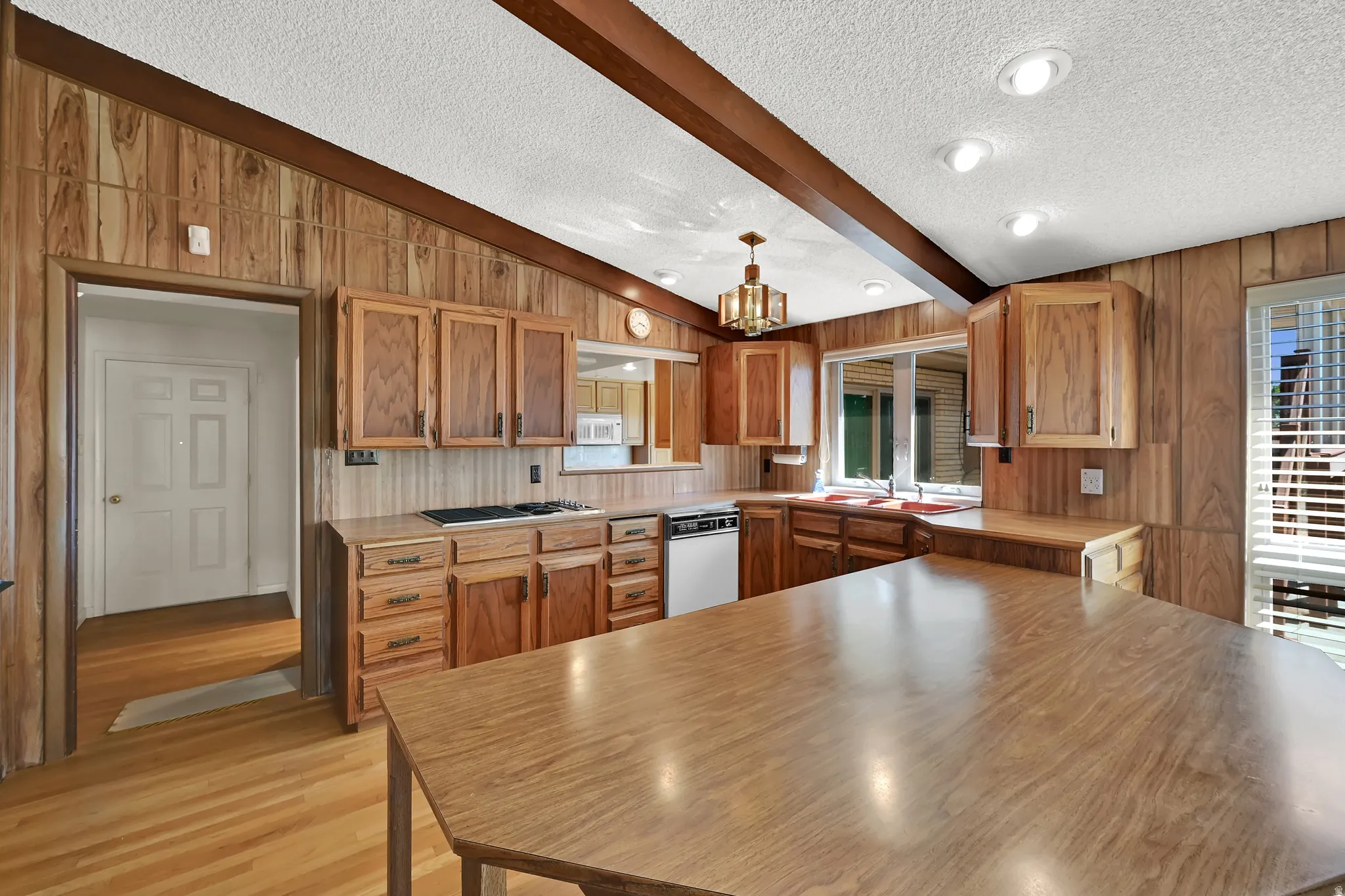 Kitchen featuring wood paneling, wood-finish flooring, wood cabinetry, a gas cooktop, and a kitchen island