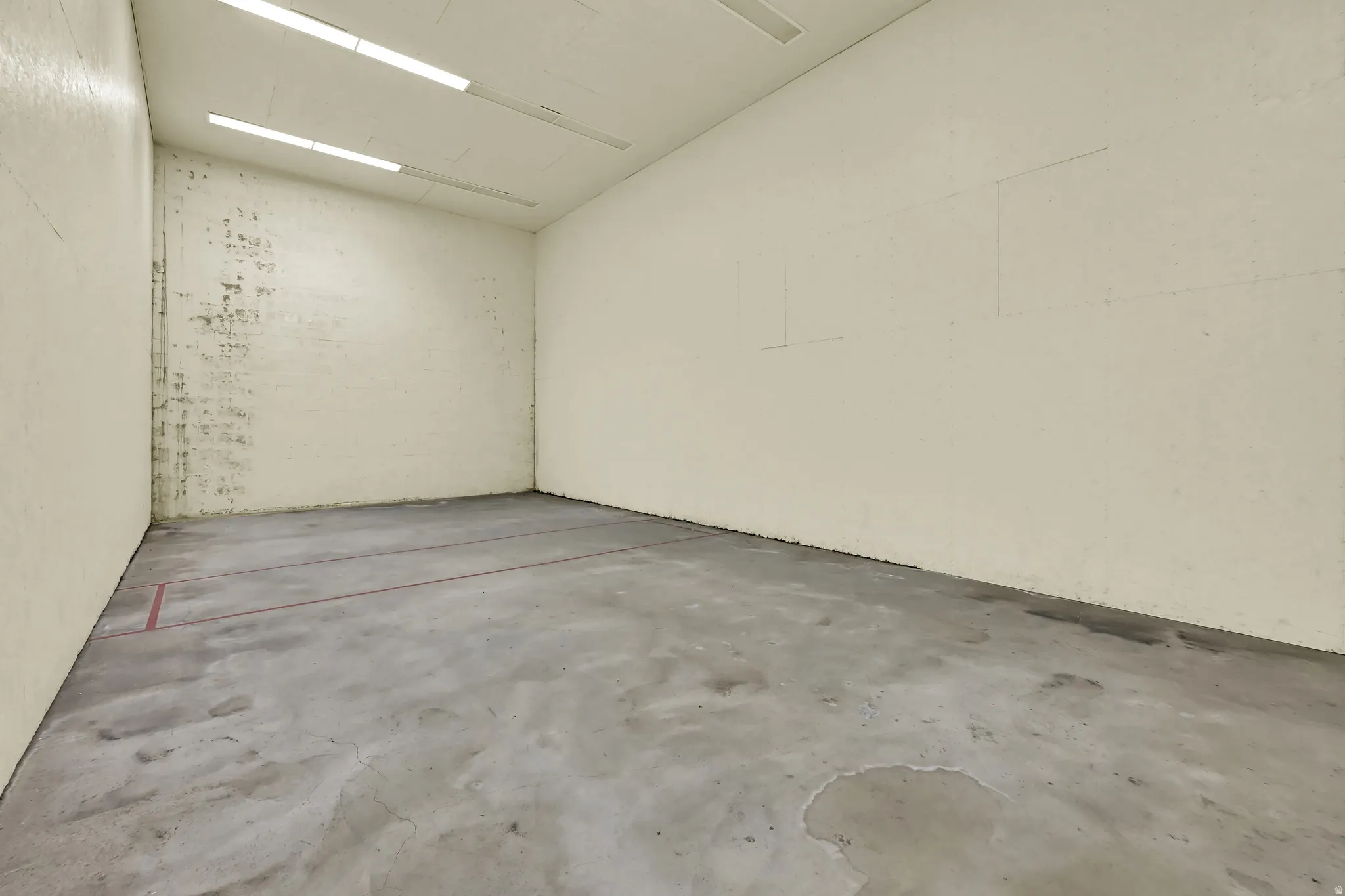Indoor court space with concrete flooring and overhead fluorescent lighting