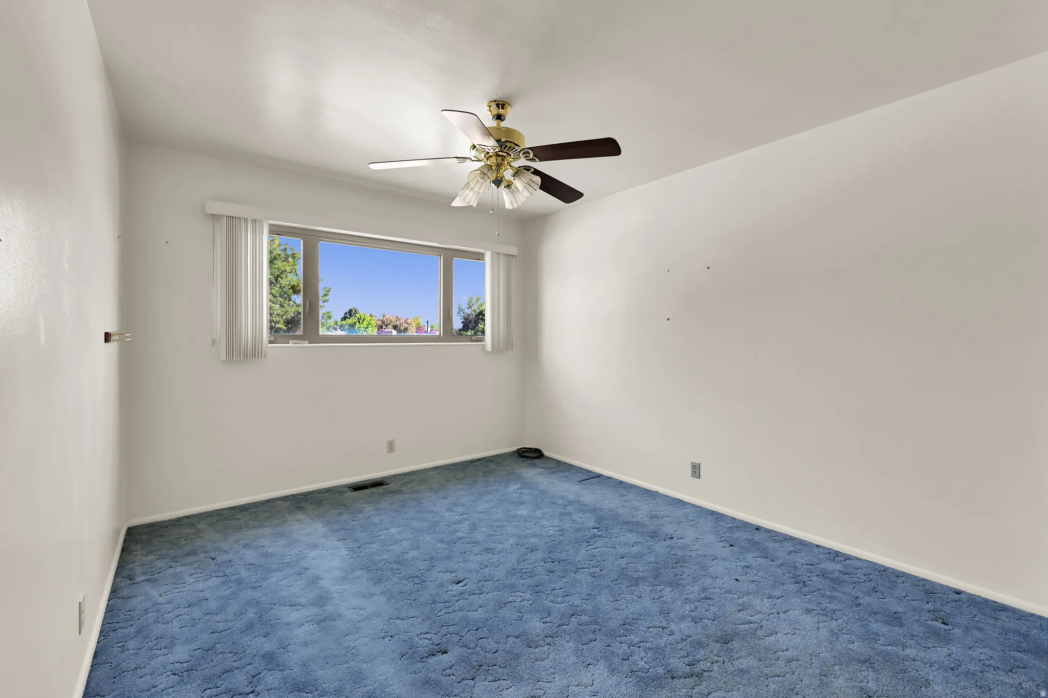 Expansive window, ceiling fan with light fixture, wall-to-wall carpeting, and painted walls