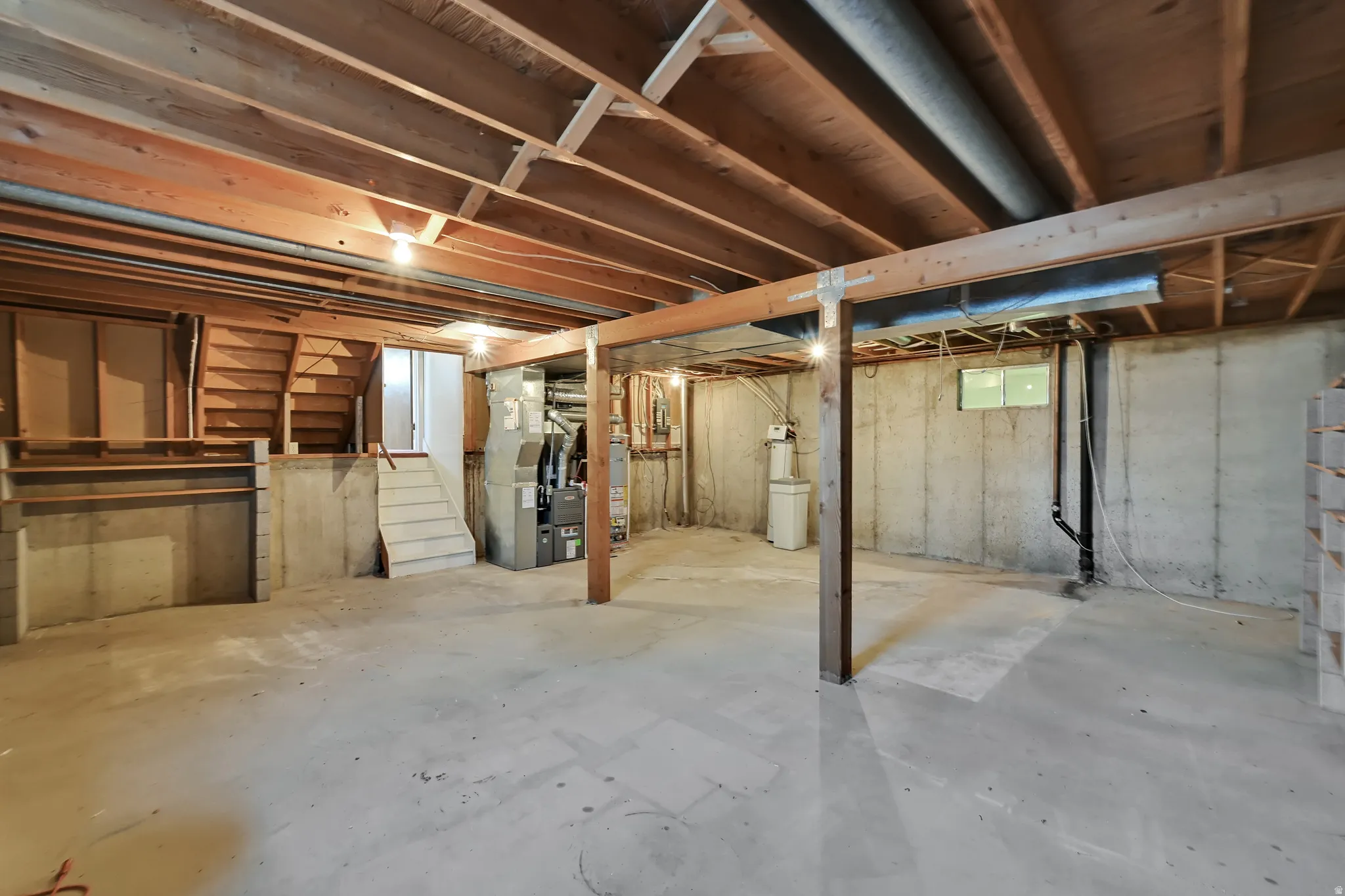 Open unfinished basement with exposed wood joists and concrete flooring