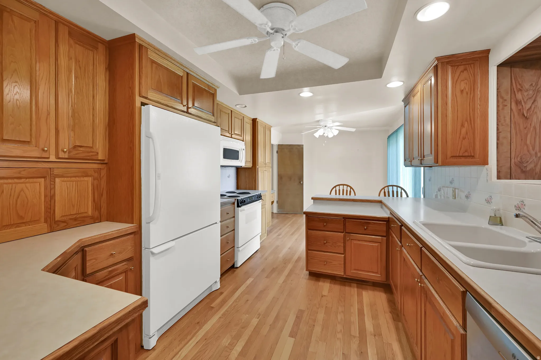 Kitchen featuring wood-finish flooring, wood cabinetry, white countertops, and a double basin sink