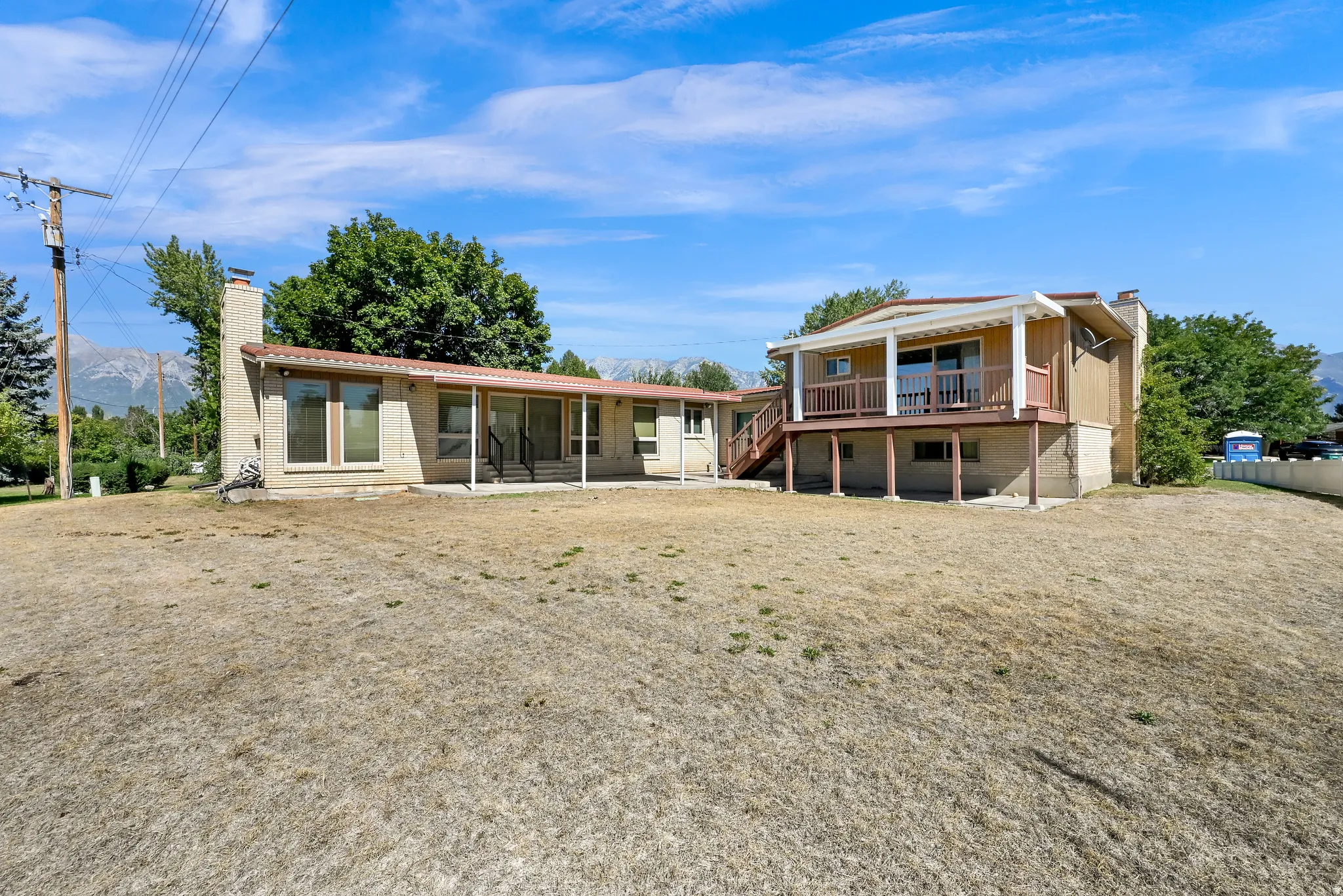 Expansive property featuring a multi-level structure with a covered balcony, an extensive brick façade, and a covered patio